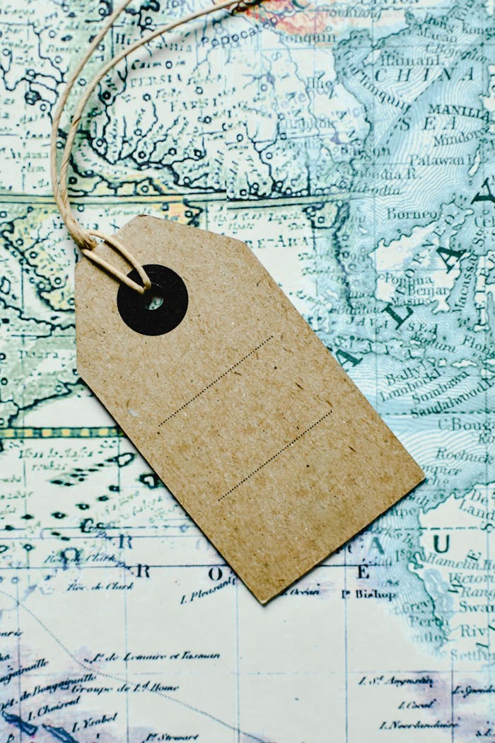 Brown paper tag placed on a vintage map, representing travel and exploration themes.